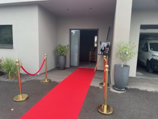 Décoration d'entrée sur le thème du casino, avec tapis rouge, cordons rouge en velours et grande affiche à l'entrée disposée sur un chevalet