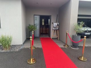 Décoration d'entrée sur le thème du casino, avec tapis rouge, cordons rouge en velours et grande affiche à l'entrée disposée sur un chevalet